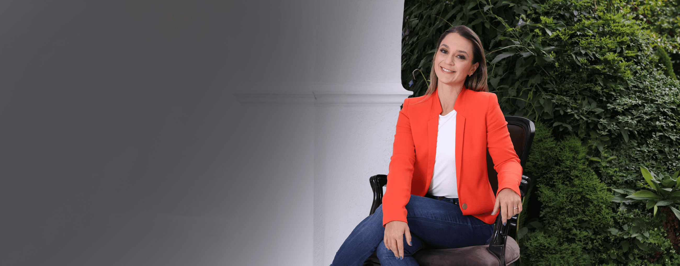 Retrato de Ju Romantini sentada em um ambiente com vegetação